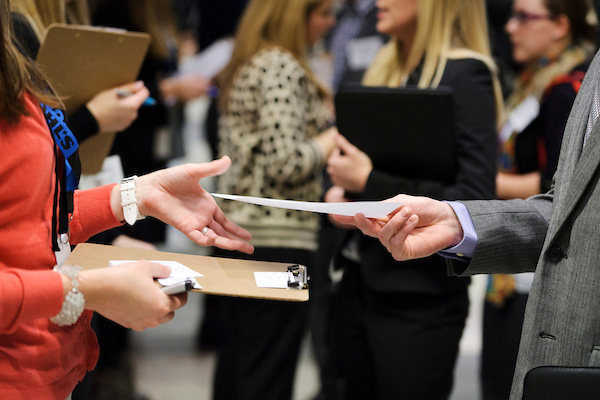 Student at a career fair handing a resume to an employer.