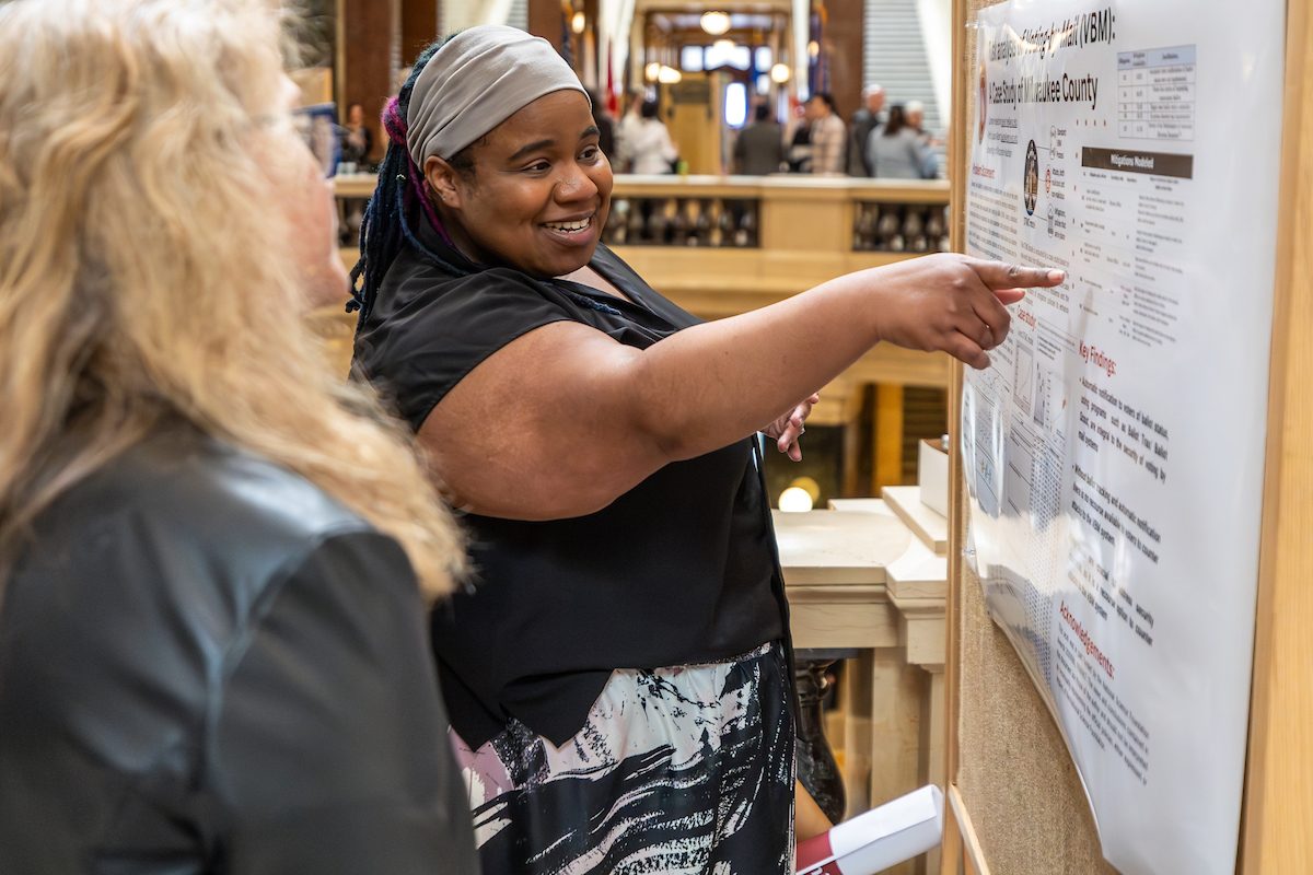 A woman pointing to a board with information